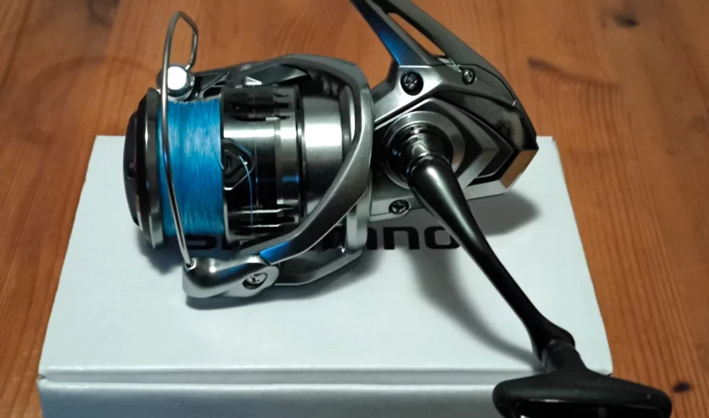 Shimano Nasci FC 4000XG spinning reel placed on its packaging box, resting on a wooden table.