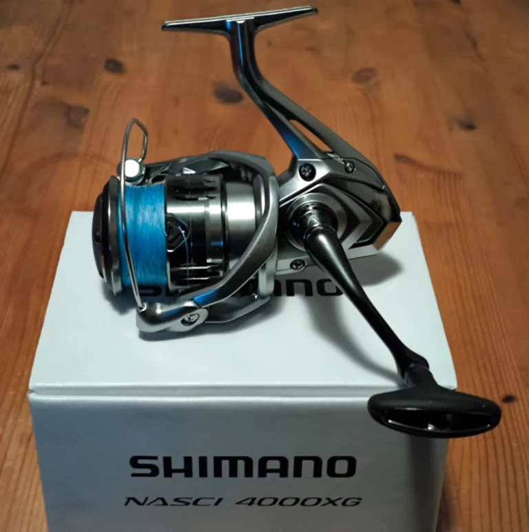 Shimano Nasci FC 4000XG spinning reel placed on its packaging box, resting on a wooden table.