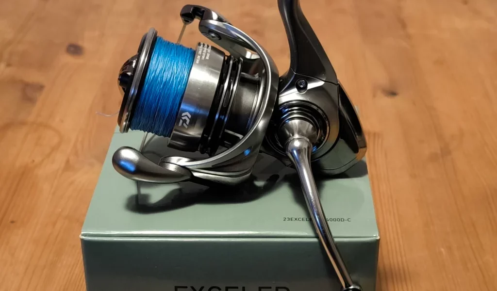 Fishing reel on a packaging box, displayed on a wooden table.
