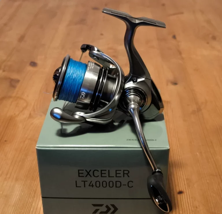 Fishing reel on a packaging box, displayed on a wooden table.